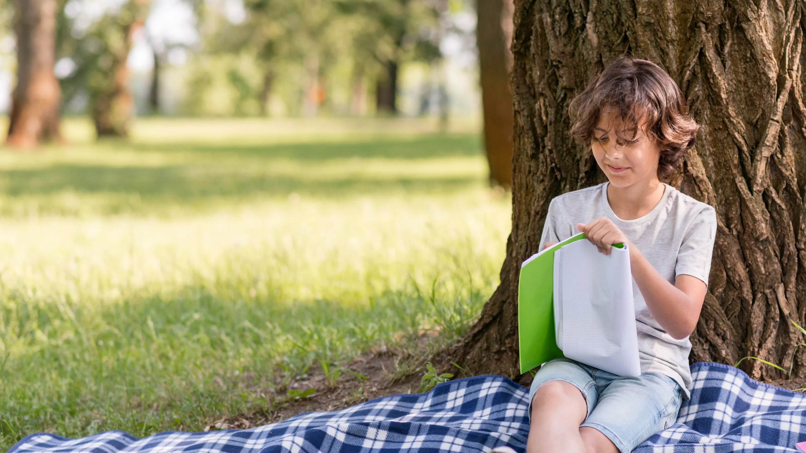 Young boy reading a book outdoors